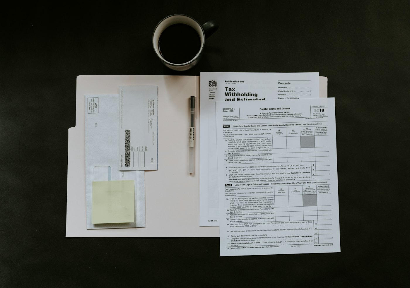 Printed forms, a pen and a mug on a dark desk